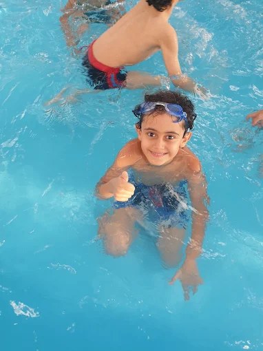 A smiling student swimming in the school pool