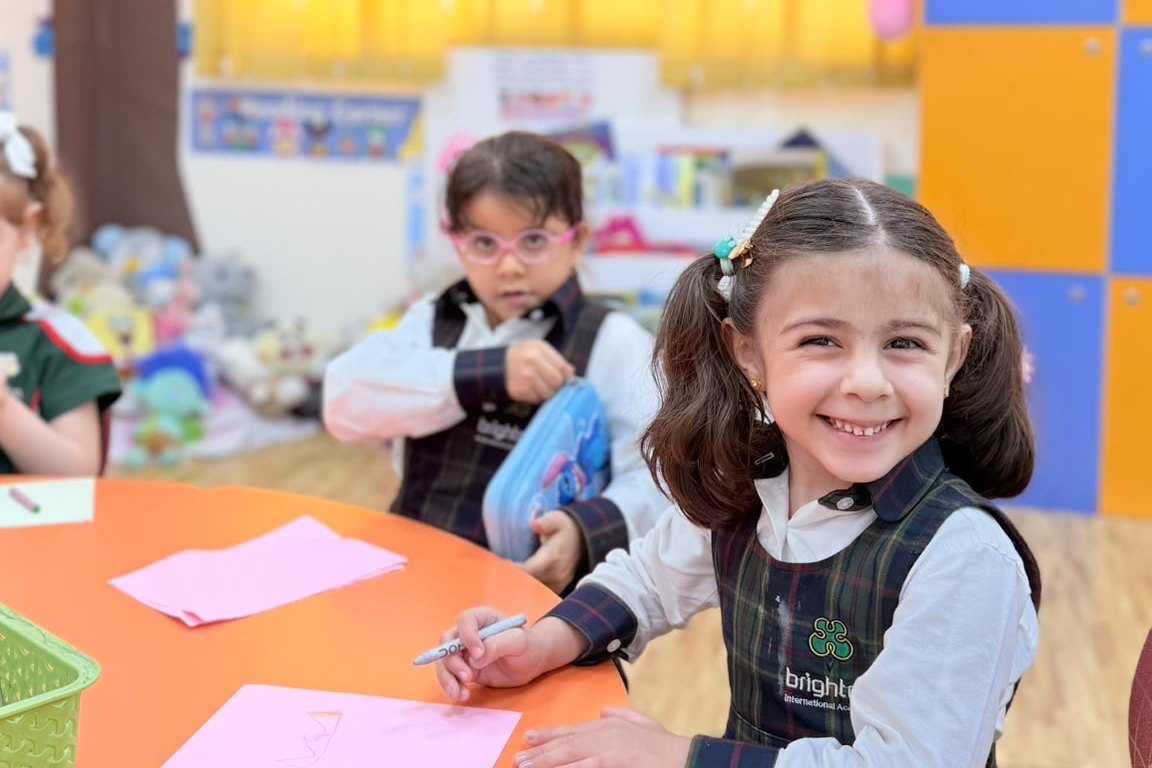 An Early Years teacher with her class, hands raised